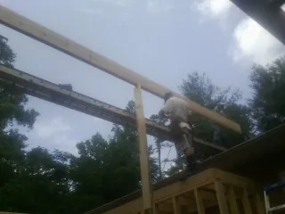 Carpenter setting a ridge beam over a new addition frame — Ice Dam Removal by Roofing Brothers in Genoa